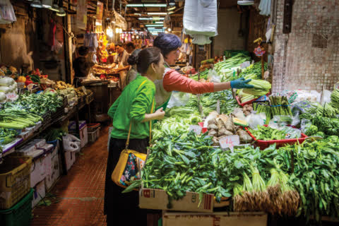 Stallholder is selecting vegetables for shopper in Tak Tin Market. Stallholder is selecting vegetables for shopper in Tak Tin Market.